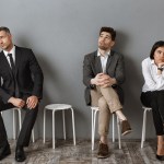 bored business people in formal wear sitting on chairs while waiting job interview